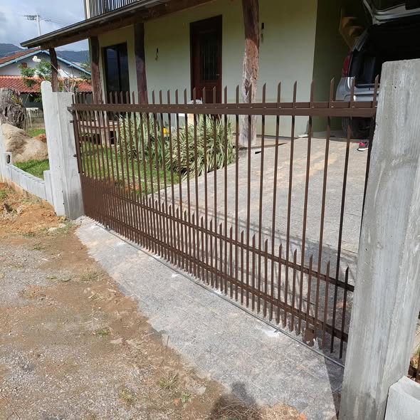 Portão de correr marrom em grade, aberto na entrada de uma casa